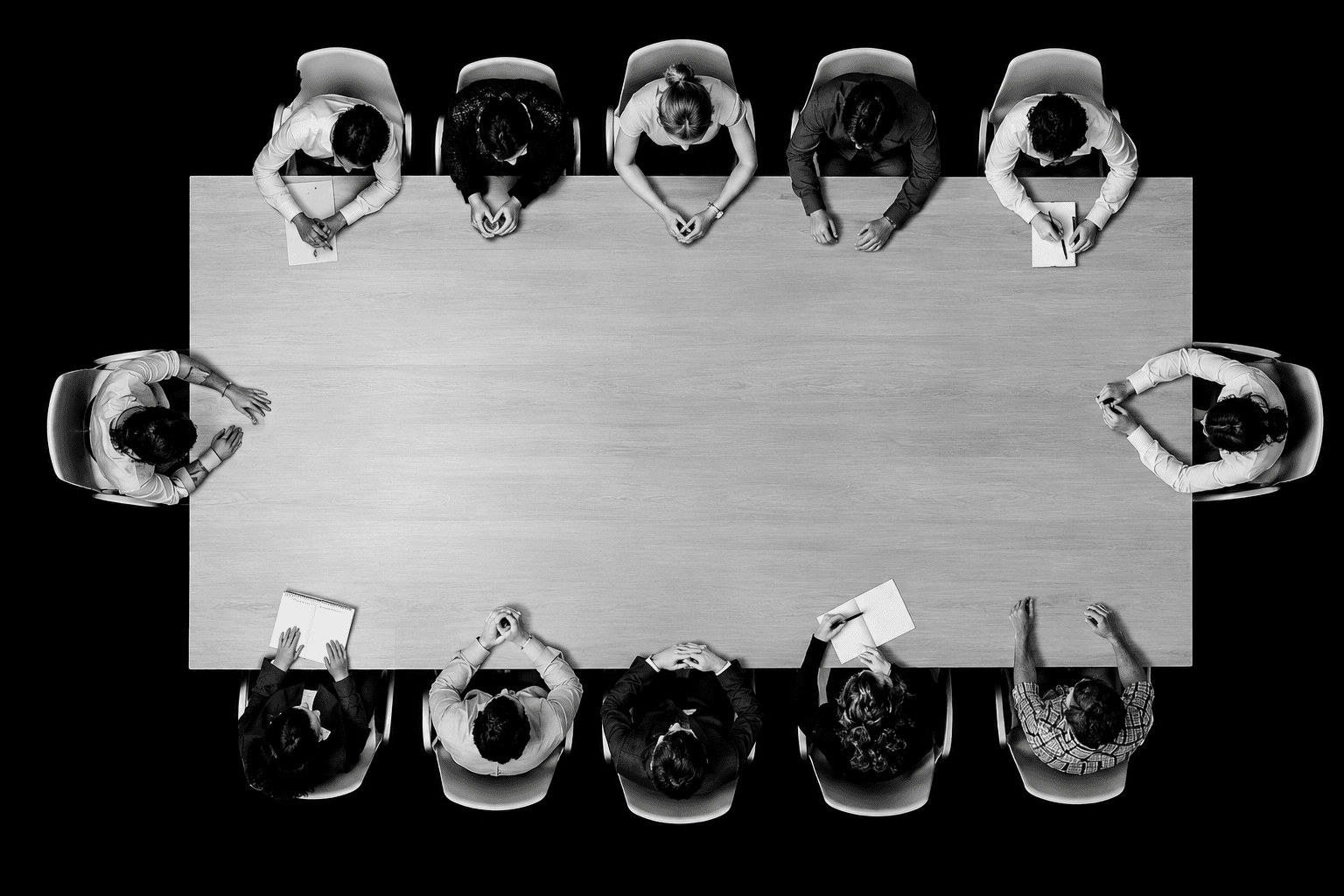 A boardroom seen from directly above: an empty table surrounded by people